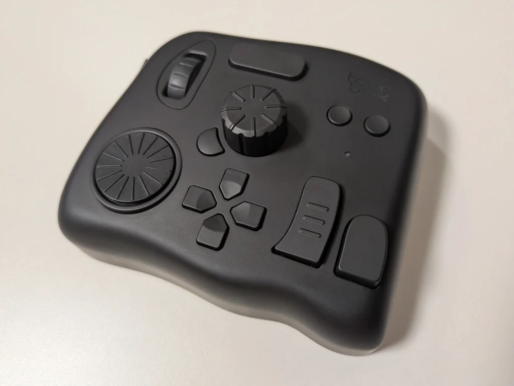 机から落下してBluetoothが故障したため、有線接続で使用しているTourBox Eliteの実機写真。長年使い込んで物理キーにテカリなどの使用感が出ているが、クリスタのダイナミックカラーピッカー機能でも現役で活躍する左手デバイス。